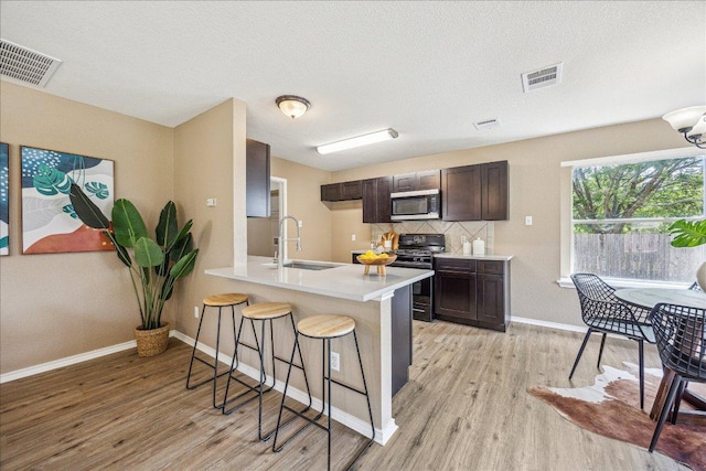 4108 Whitecrest Cv, Round Rock, TX 78681 - kitchen featuring stainless steel microwave, black gas stove, light wood-style flooring, and a kitchen breakfast bar