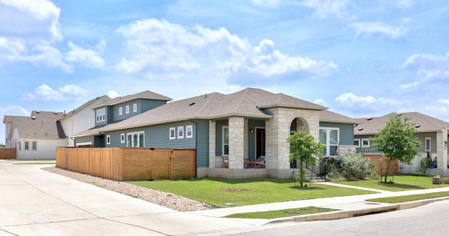 7901 Donnelley Dr, Austin, TX 78744 - view of front of property featuring driveway, stone siding, roof with shingles, a front yard, and fence
