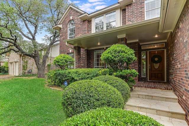 view of exterior entry with a yard, brick siding, and a garage