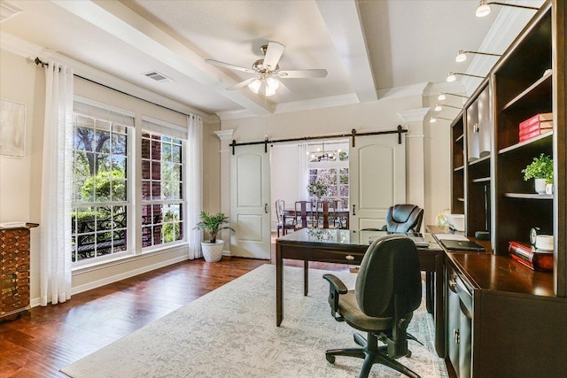 office featuring a barn door, visible vents, wood finished floors, and a wealth of natural light