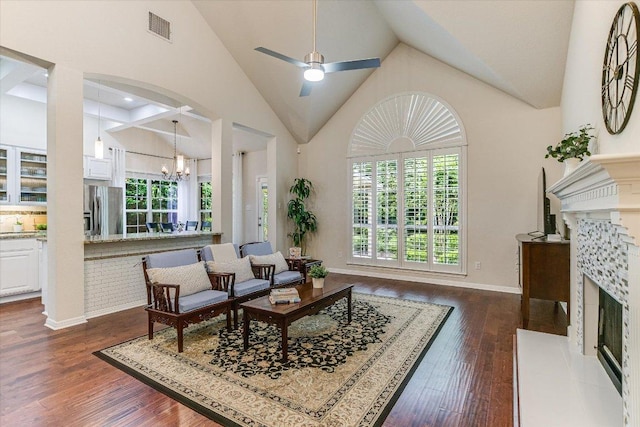 living room featuring visible vents, a high end fireplace, dark wood finished floors, high vaulted ceiling, and ceiling fan with notable chandelier