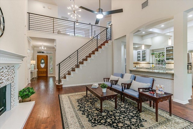 living room with wood finished floors, visible vents, stairway, and a high ceiling