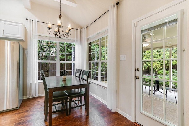 dining area with dark wood-style flooring, a chandelier, vaulted ceiling, and baseboards