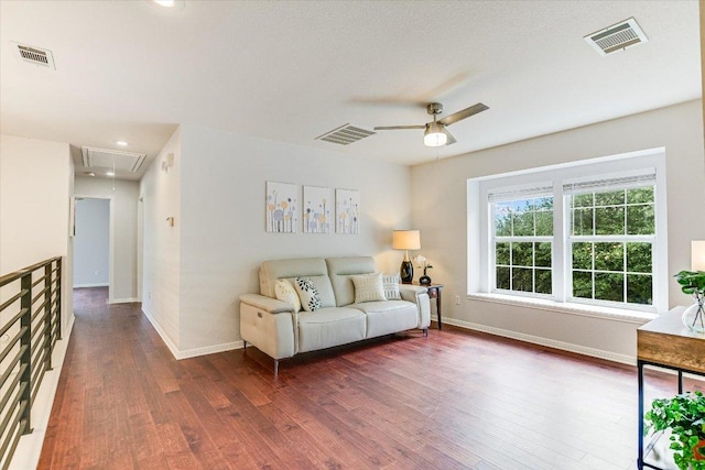 living room with attic access, visible vents, dark wood-style floors, and baseboards