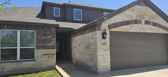 1337 Violet Ln, Kyle, TX 78640 - view of property exterior featuring stone siding, a garage, and a shingled roof