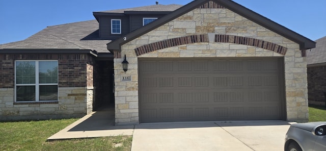 1337 Violet Ln, Kyle, TX 78640 - view of front of property featuring concrete driveway, stone siding, an attached garage, and a shingled roof