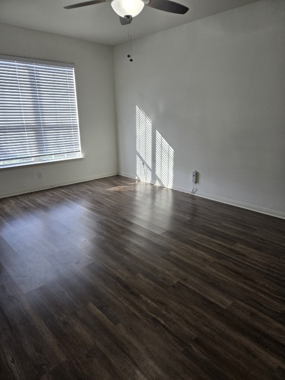 1337 Violet Ln, Kyle, TX 78640 - unfurnished room with dark wood-type flooring, a ceiling fan, and baseboards
