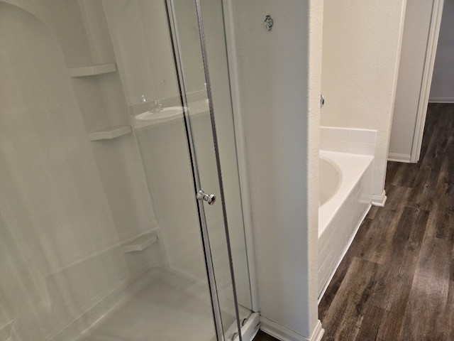 1337 Violet Ln, Kyle, TX 78640 - bathroom featuring a shower stall, wood finished floors, a garden tub, and baseboards