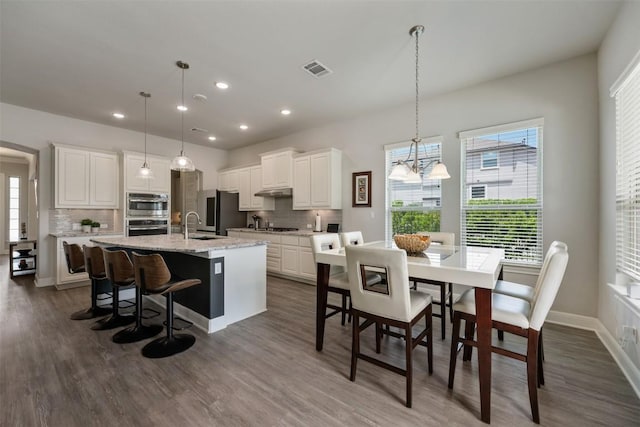 1728 Siena Sunset Rd, Leander, TX 78641 - kitchen with visible vents, an inviting chandelier, a kitchen island with sink, white cabinets, and tasteful backsplash