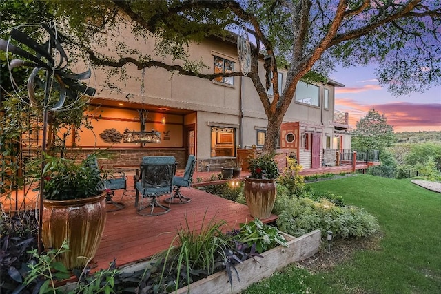611 N Cuernavaca Dr Unit 301, Austin, TX 78733 - back of property at dusk with a wooden deck, a yard, and stucco siding