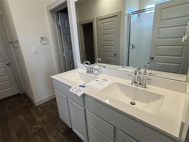 bathroom with baseboards, wood finished floors, an enclosed shower, and a sink