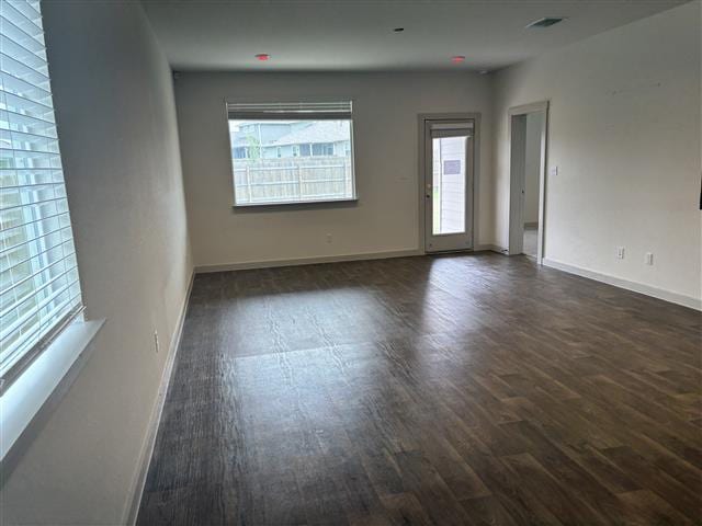 unfurnished room with visible vents, dark wood finished floors, and baseboards