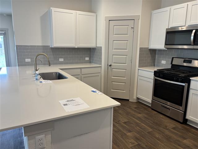 115 Big Cypress Bayou Rd, Hutto, TX 78634 - kitchen featuring appliances with stainless steel finishes, a sink, light countertops, and white cabinetry