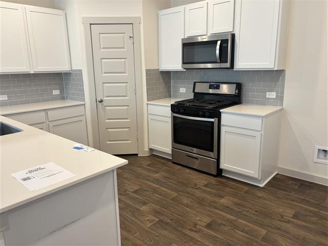 kitchen with appliances with stainless steel finishes, dark wood-type flooring, light countertops, and white cabinets
