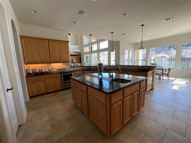 kitchen with visible vents, a sink, wine cooler, and a healthy amount of sunlight