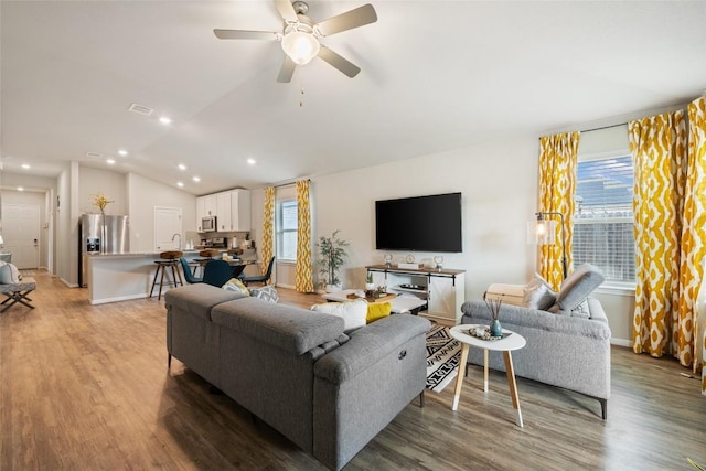 living area featuring a wealth of natural light, light wood-style floors, lofted ceiling, and ceiling fan