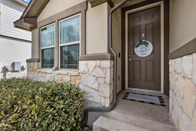 property entrance featuring stucco siding and stone siding