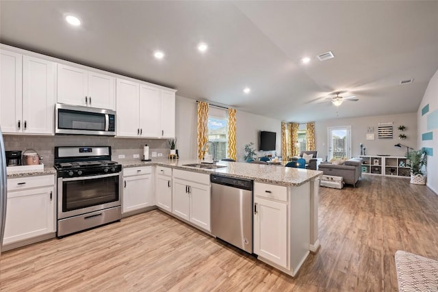 kitchen with a sink, visible vents, stainless steel appliances, a healthy amount of sunlight, and a peninsula