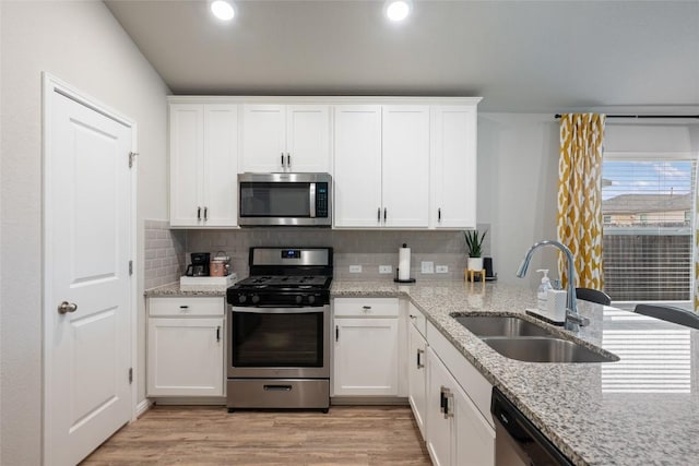 kitchen with light wood-style flooring, a sink, white cabinets, and appliances with stainless steel finishes
