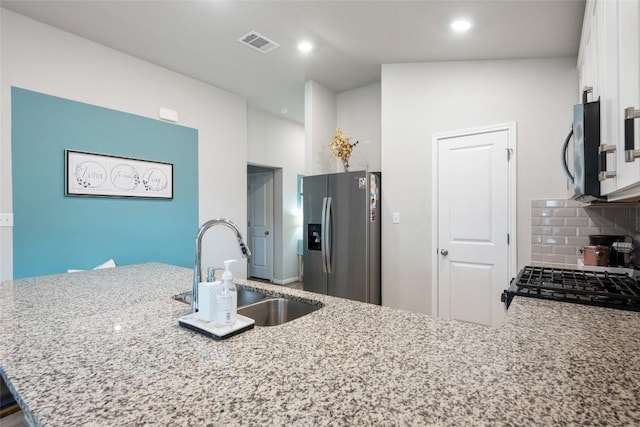 kitchen featuring light stone countertops, stainless steel appliances, white cabinets, a sink, and visible vents