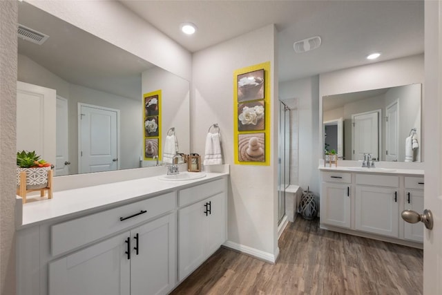 full bath featuring a shower stall, a sink, visible vents, baseboards, and wood finished floors