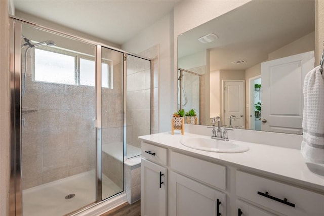 bathroom featuring wood finished floors, vanity, a shower stall, and visible vents