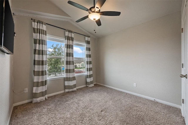 empty room with ceiling fan, vaulted ceiling, carpet floors, and baseboards