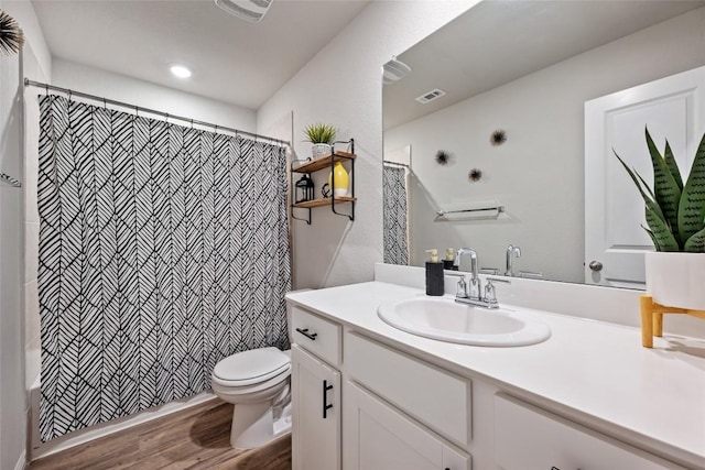 bathroom with visible vents, a shower with shower curtain, toilet, wood finished floors, and vanity