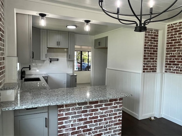 5611 Joe Sayers Ave, Austin, TX 78756 - kitchen featuring a sink, gray cabinetry, a peninsula, light stone countertops, and wainscoting