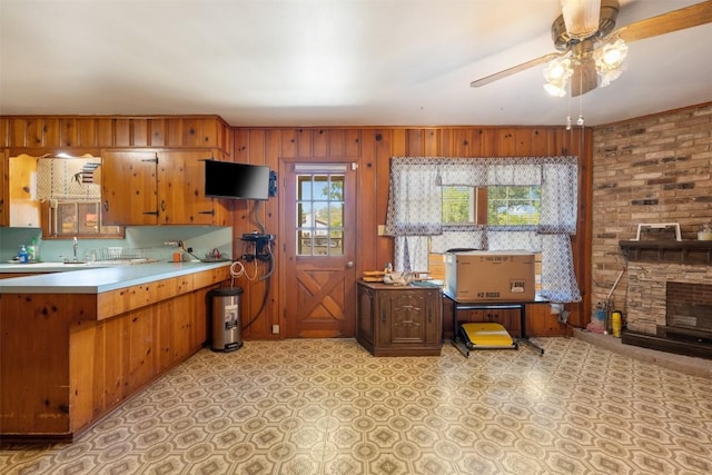 kitchen featuring light floors, light countertops, brown cabinets, wood walls, and ceiling fan