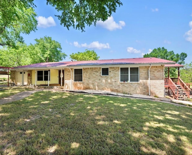 single story home with stairway, metal roof, a front yard, and brick siding