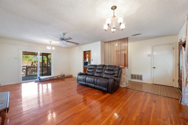 living area with a textured ceiling, visible vents, wood finished floors, and ceiling fan with notable chandelier
