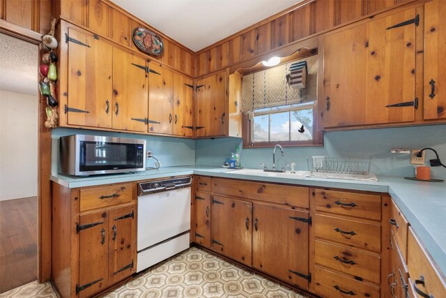 3602 Ferguson Ln, Austin, TX 78754 - kitchen featuring stainless steel microwave, white dishwasher, light countertops, and brown cabinetry
