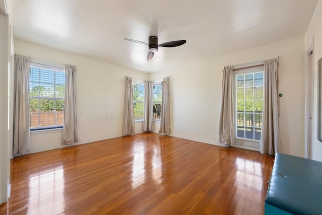 unfurnished room featuring a ceiling fan, wood finished floors, and baseboards