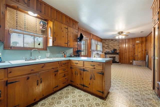 kitchen with a sink, a peninsula, brown cabinetry, and light countertops
