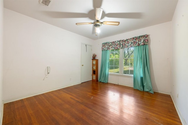 empty room featuring wood finished floors, a ceiling fan, and visible vents