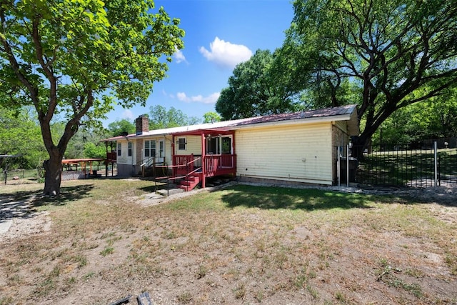 ranch-style house with a front yard, a chimney, and fence