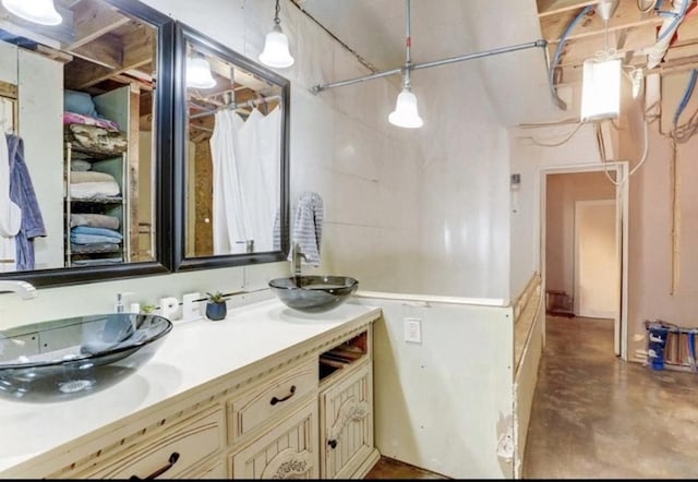 bathroom featuring double vanity, a sink, and concrete flooring