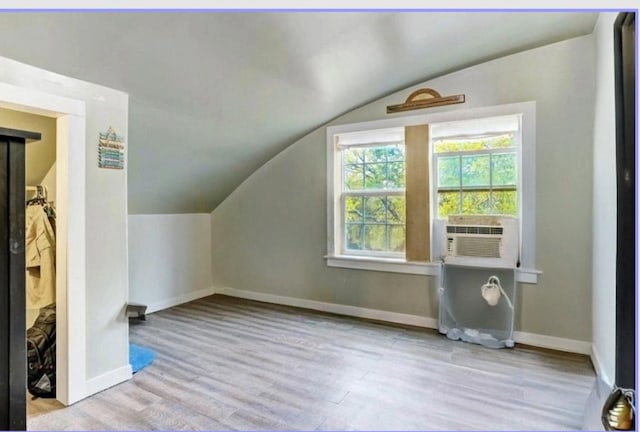 additional living space with wood finished floors, cooling unit, vaulted ceiling, and baseboards