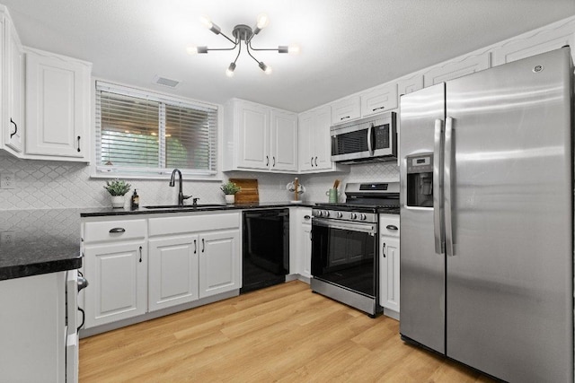 10416 Doering Ln, Austin, TX 78750 - kitchen featuring appliances with stainless steel finishes, dark countertops, white cabinetry, light wood-type flooring, and backsplash