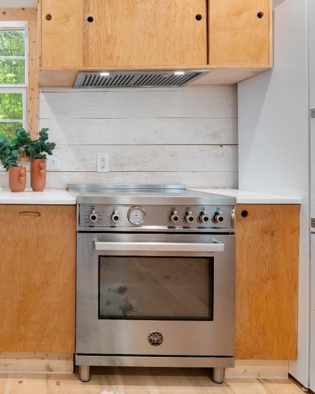 1405 Cometa St, Austin, TX 78721 - kitchen view of stainless steel stove, light countertops, ventilation hood, and wooden walls