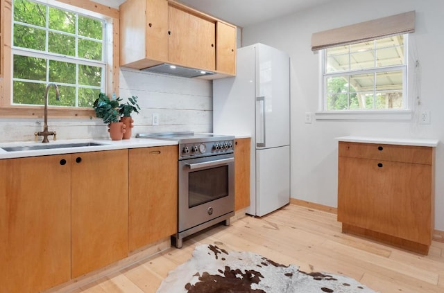 1405 Cometa St, Austin, TX 78721 - kitchen with high end stove, light wood-style floors, freestanding refrigerator, light countertops, and ventilation hood