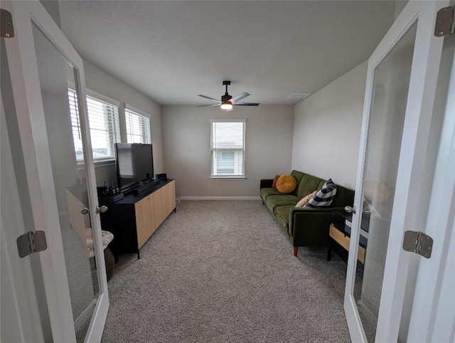 living area with baseboards, ceiling fan, french doors, and light colored carpet