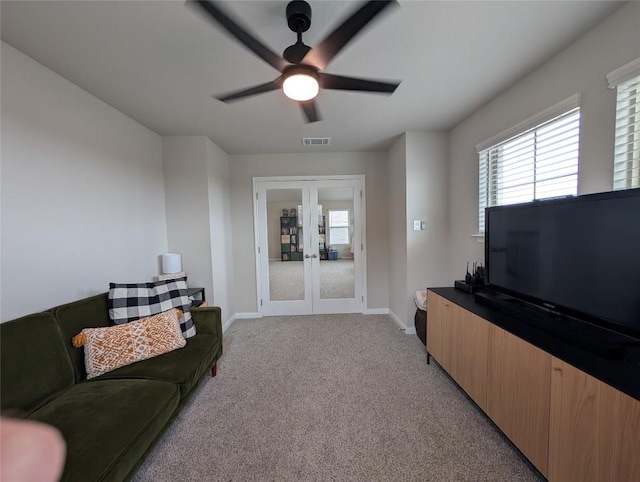 living area with light carpet, baseboards, visible vents, a ceiling fan, and french doors