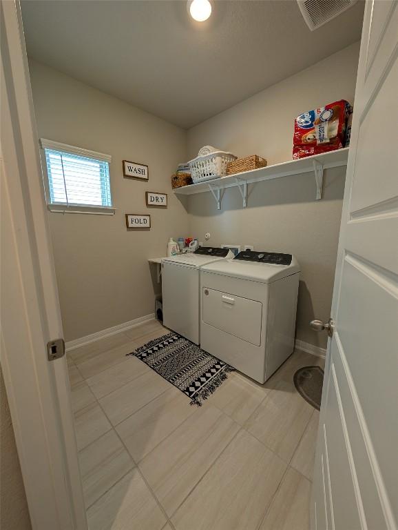 clothes washing area featuring visible vents, baseboards, laundry area, and washing machine and dryer