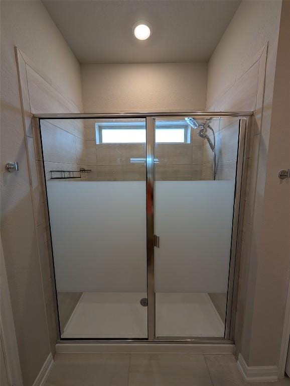 full bath with a healthy amount of sunlight, tile patterned flooring, and a stall shower