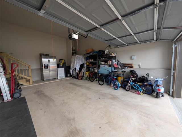 garage with a garage door opener and stainless steel fridge