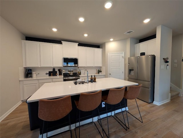 kitchen featuring light wood finished floors, a sink, stainless steel appliances, and visible vents