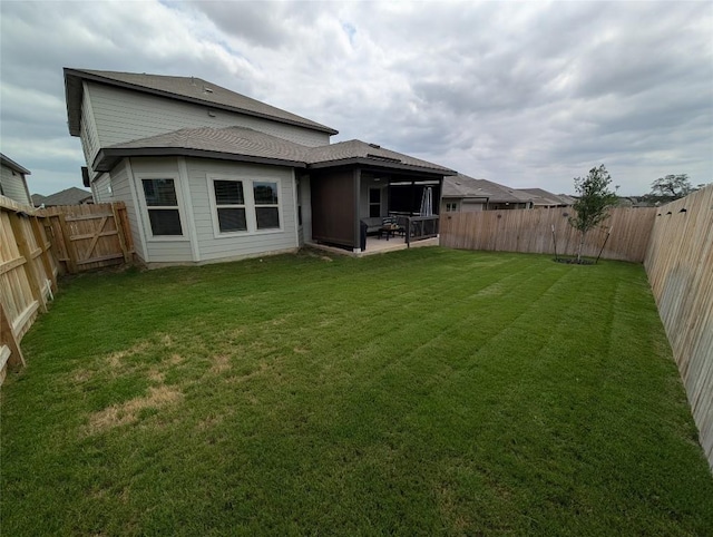 rear view of property featuring a lawn, a patio, and a fenced backyard