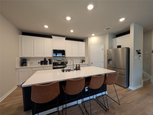 kitchen with visible vents, light wood-style floors, appliances with stainless steel finishes, and a sink